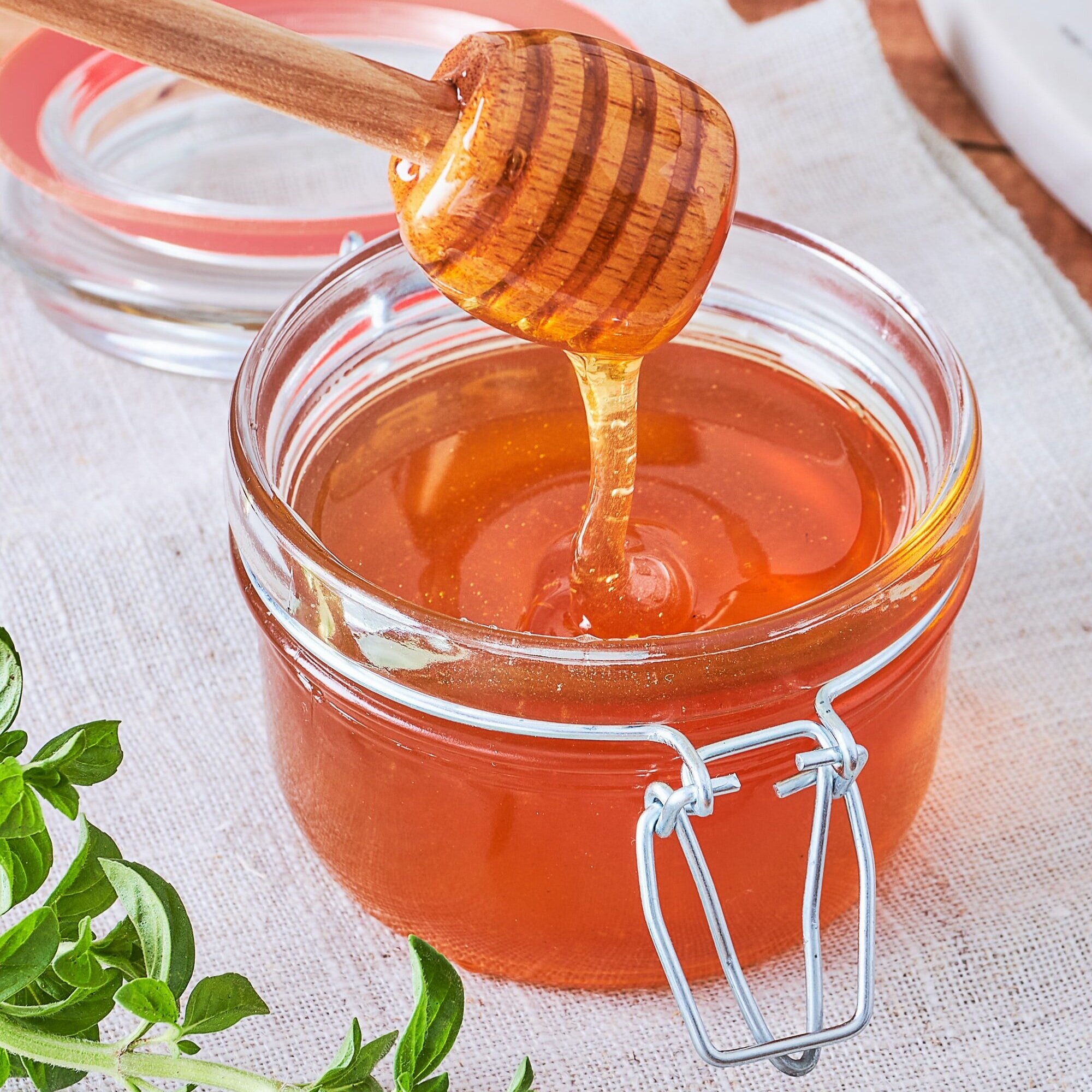 Person holding a glass milk bottle tied with twine, wearing a plaid shirt, with a blurred green garden background. Ideal for topics on homemade dairy, sustainability, or organic farming.